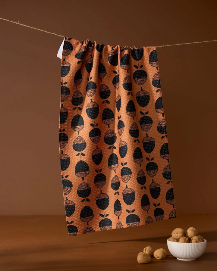 Fabric with black acorn pattern hanging on a line against a brown background