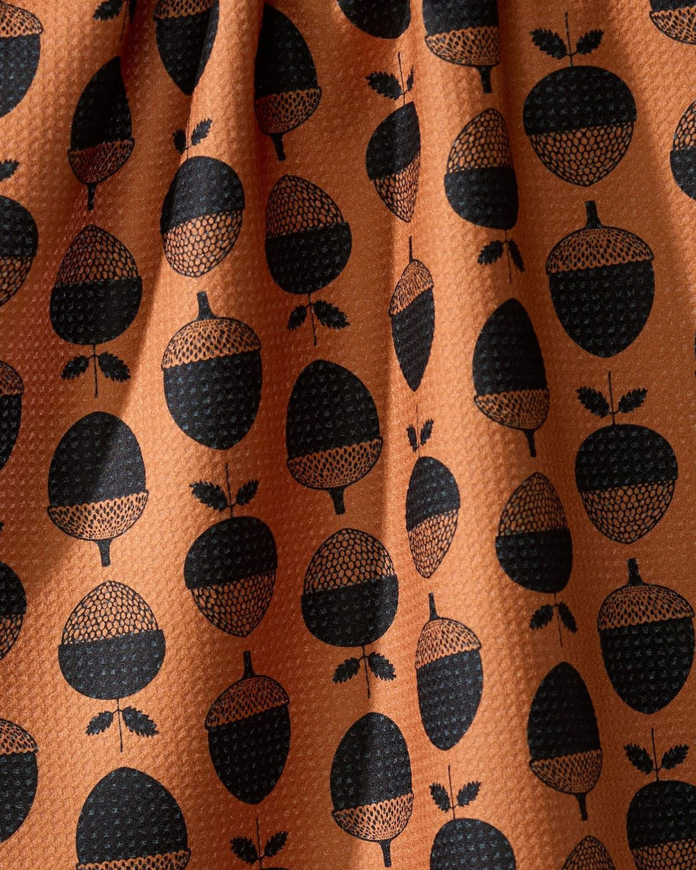Pattern of black acorns on a brown background