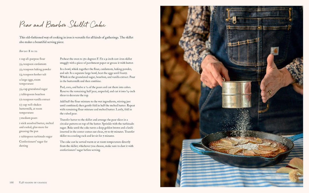 Person seasoning food in a skillet with a sifter, next to a recipe on a wooden surface.