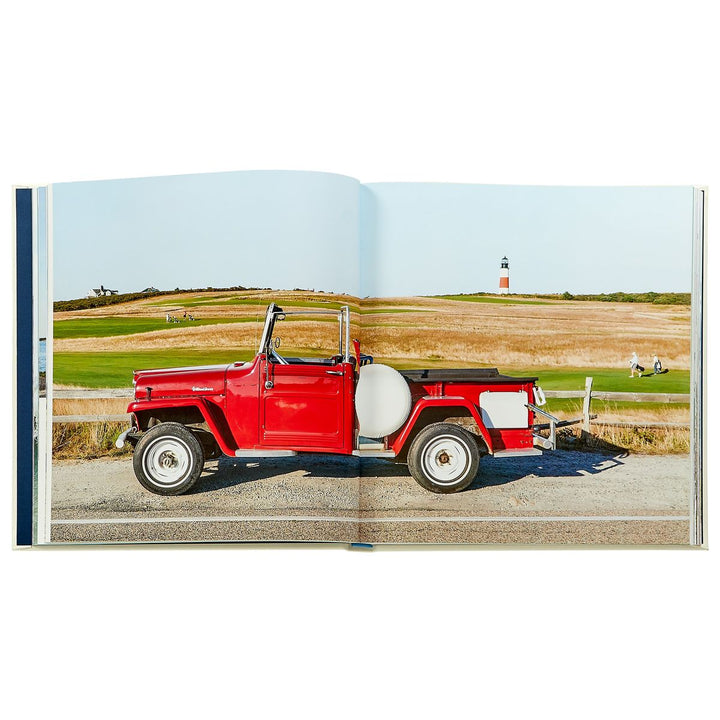 Open book showing a red vintage jeep on a scenic road with a lighthouse in the background.