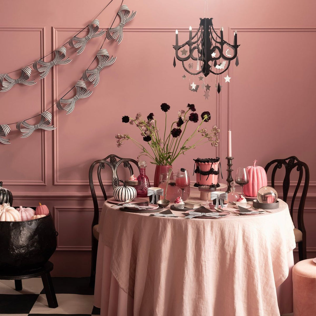 Dining room with a pink tablecloth, black chandelier, and Halloween-themed decor.