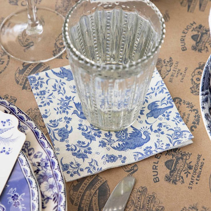 Clear glass on a blue and white patterned napkin with a brown paper background featuring branding.