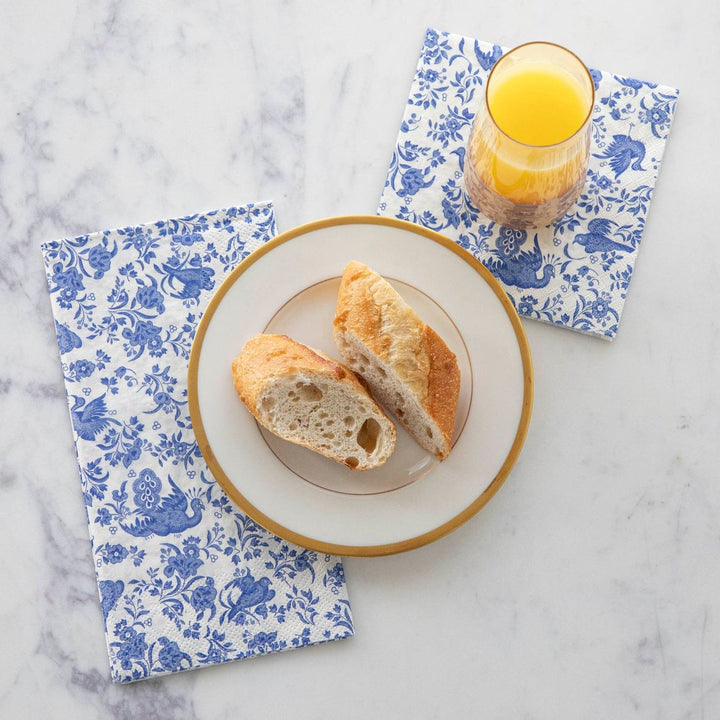 Breakfast scene with bread on a plate and orange juice on floral-patterned napkins.