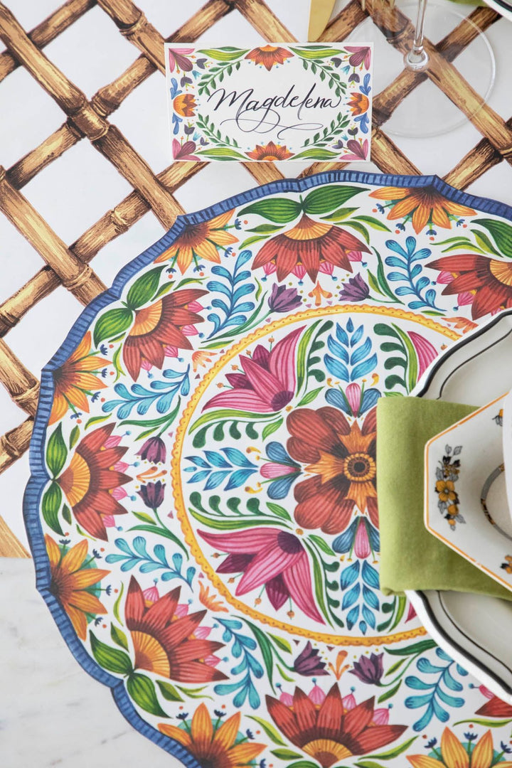 Colorful floral placemat on a woven mat with a name card in the background
