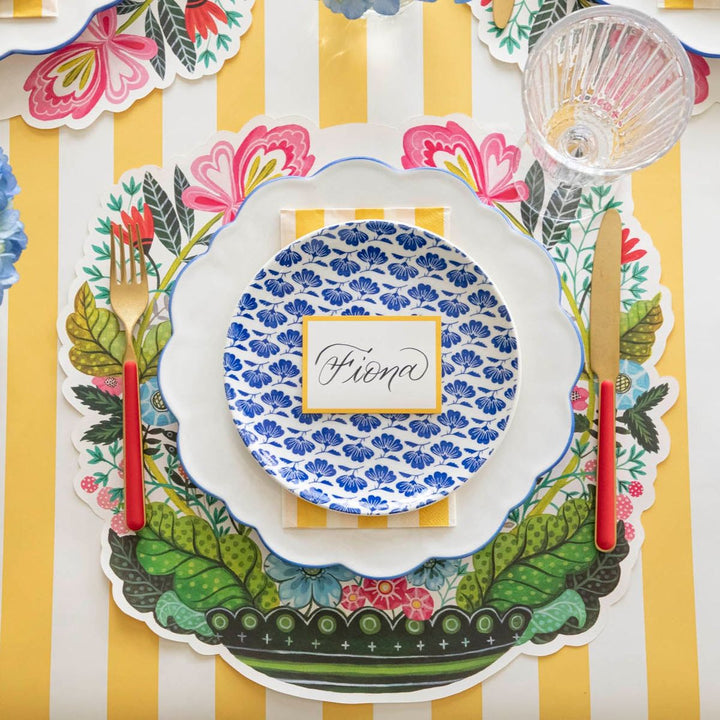 Colorful table setting with floral and leaf patterns on a striped yellow and white background.