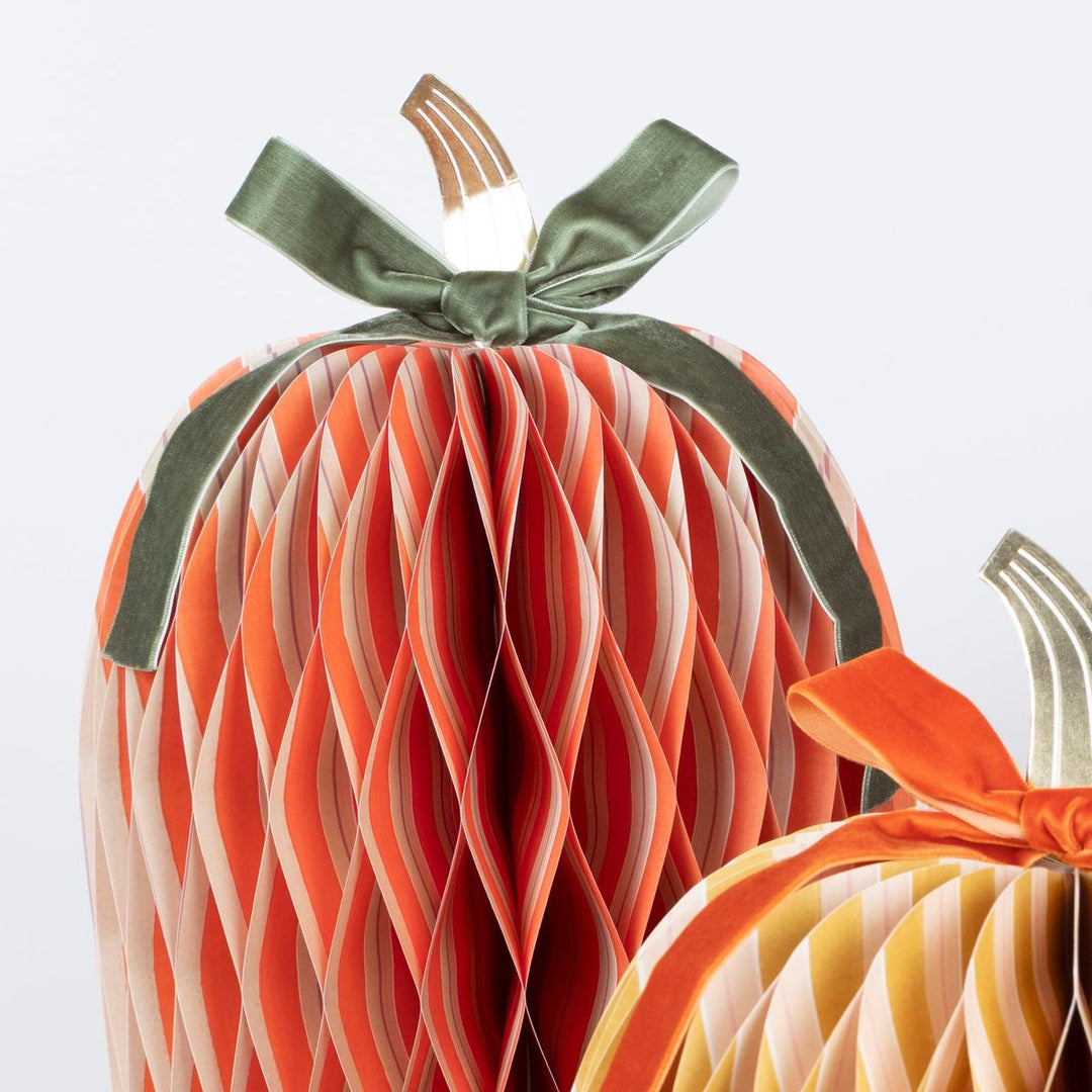 Decorative paper pumpkins with ribbons on a white background