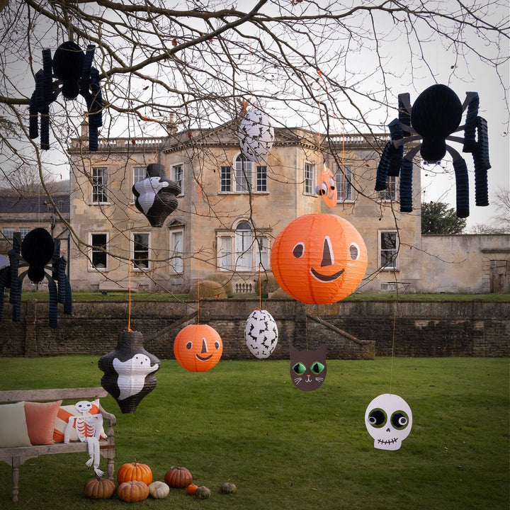 Halloween decorations including pumpkins, ghosts, and spiders in front of a large building.