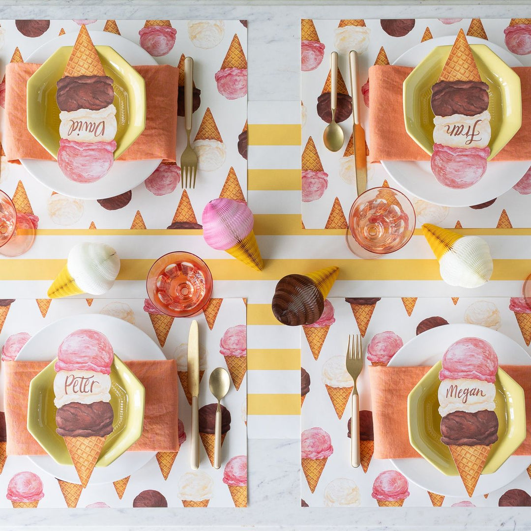 Table setting with ice cream cone-themed plates and placemats on a marble surface.