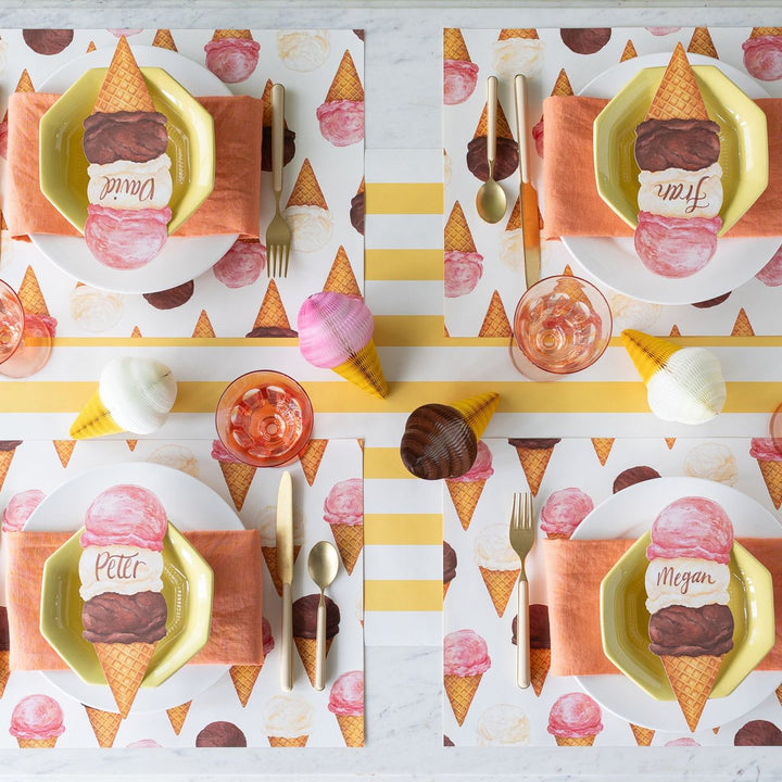 Table setting with ice cream cone-themed plates and placemats on a marble surface.