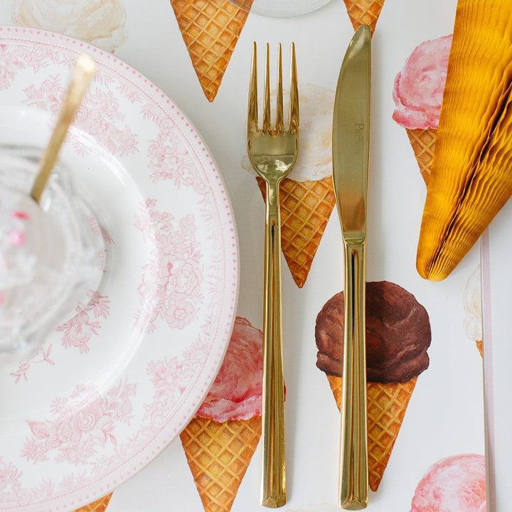 Gold cutlery on a table setting with ice cream cone-themed placemats.