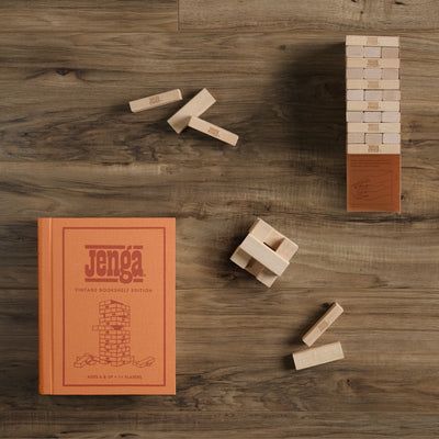 Jenga game set on a wooden surface with the Jenga book visible.