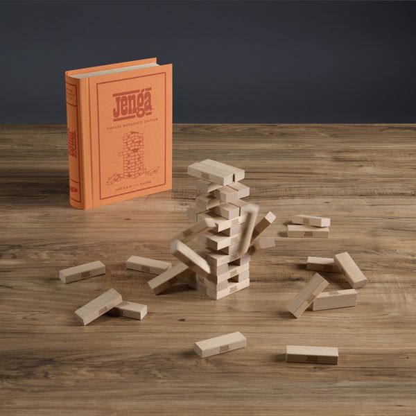 Jenga game with wooden blocks and orange instruction book on a wooden surface