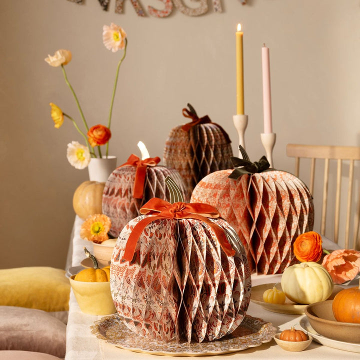 Decorative paper pumpkins on a table with flowers and candles