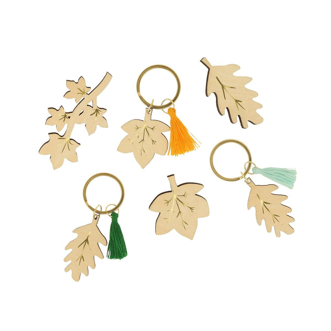 Set of leaf-shaped keychains with colorful tassels on a white background