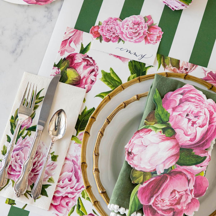 Table setting with floral placemats, plates, and cutlery on a marble surface.