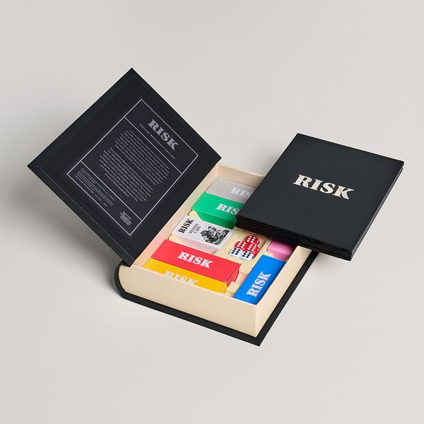 Open book with 'Risk' game components on a light gray background