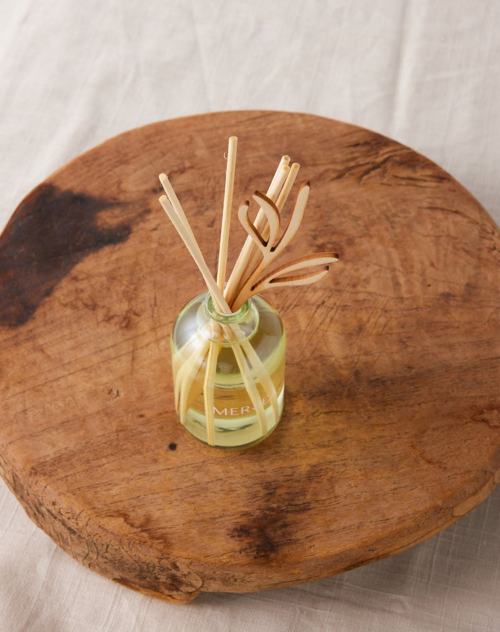 Diffuser with sticks in a glass bottle on a wooden surface