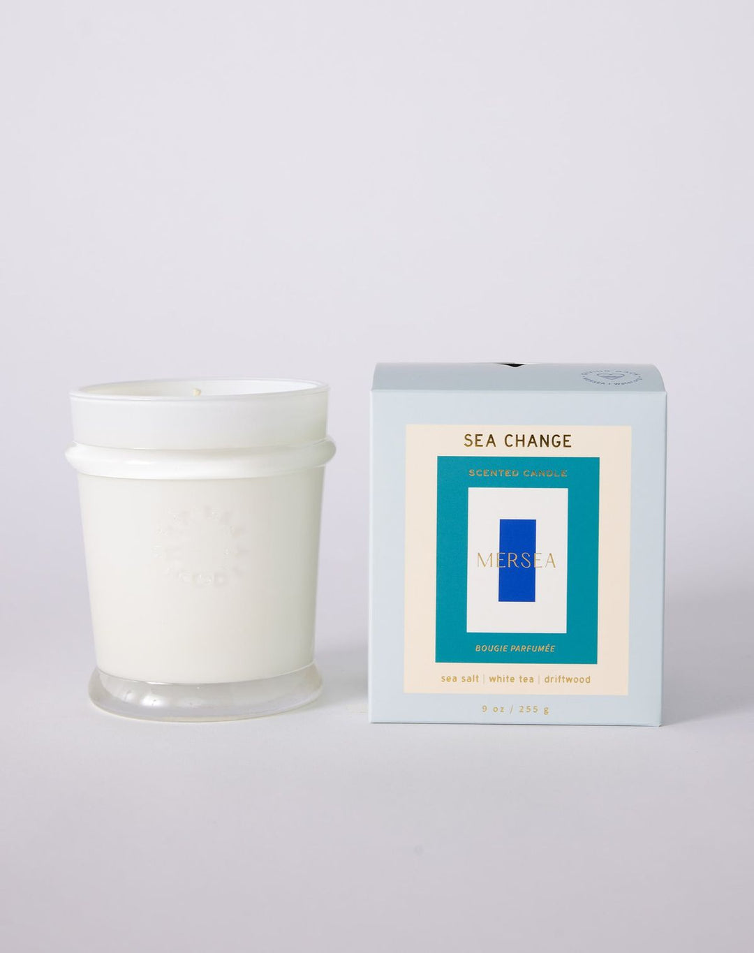White candle with 'Sea Change' packaging on a light gray background