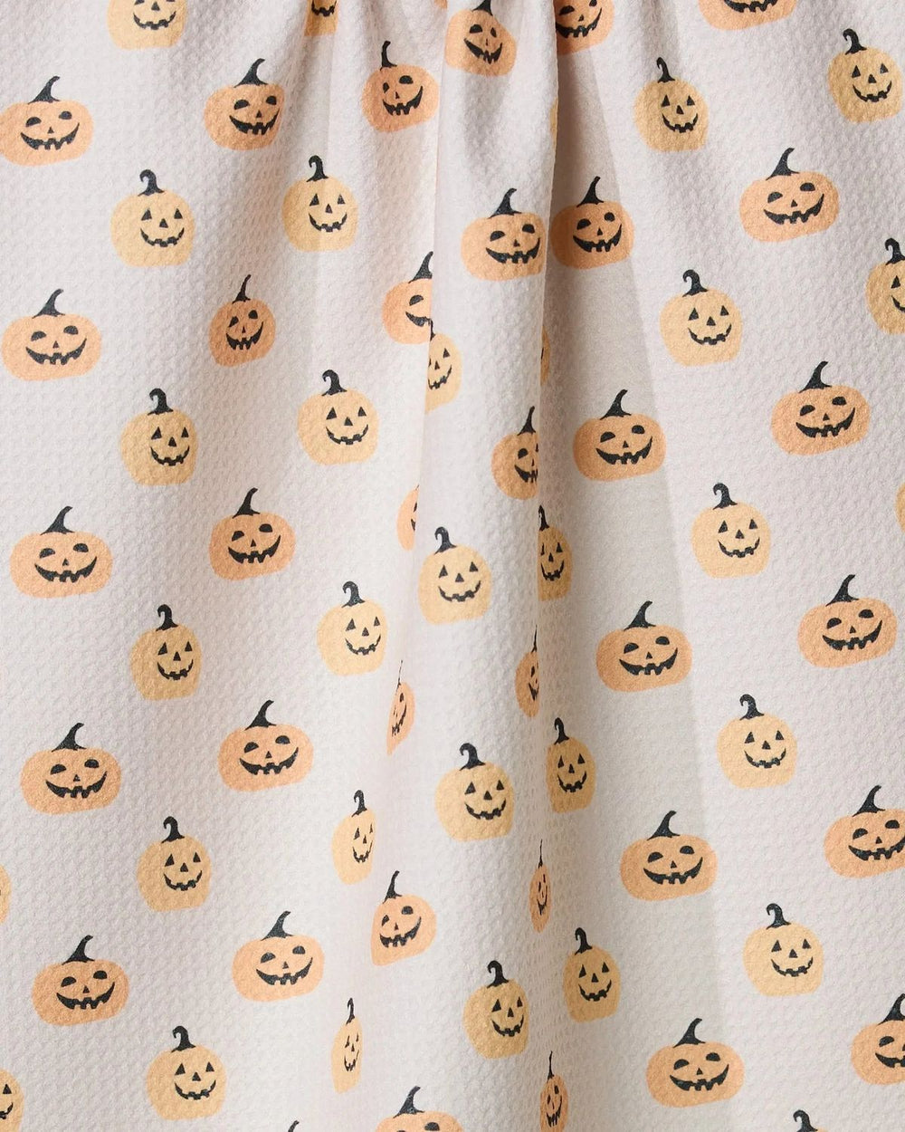 Fabric with Halloween-themed pumpkin pattern on a beige background