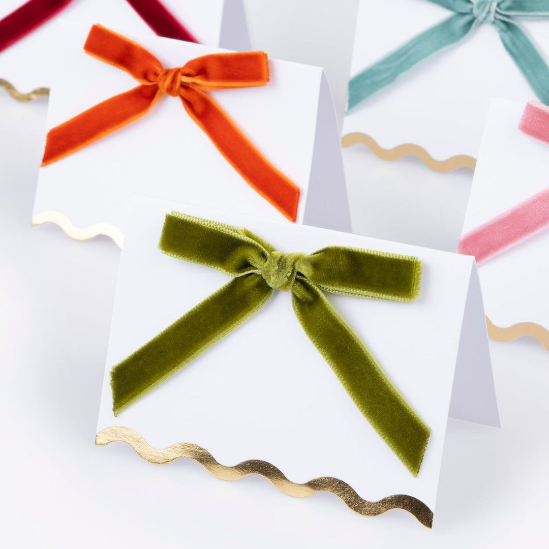 Colorful velvet bows on white cards with gold ribbons on a light gray background