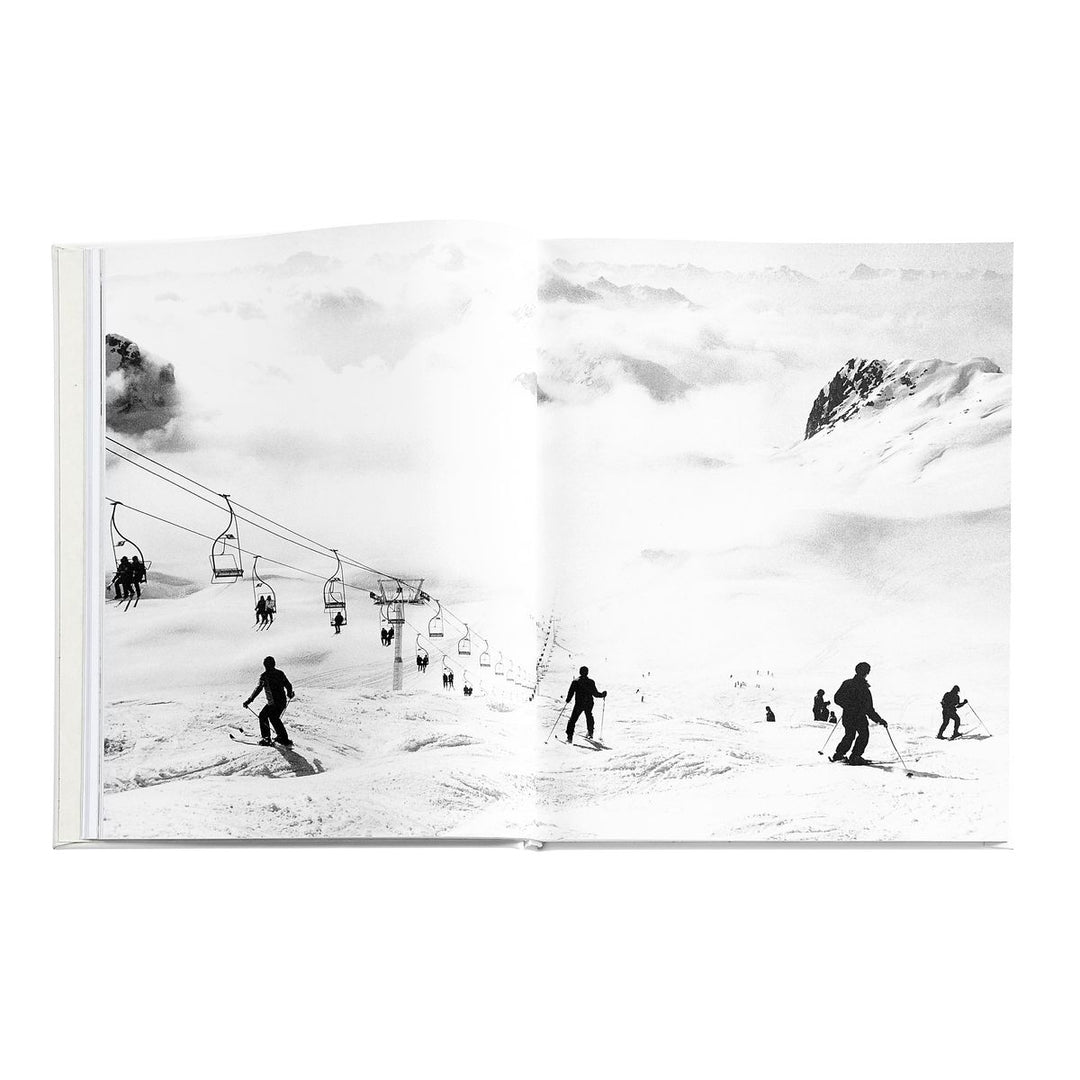 Black and white photo of skiers on a snowy mountain with a ski lift.