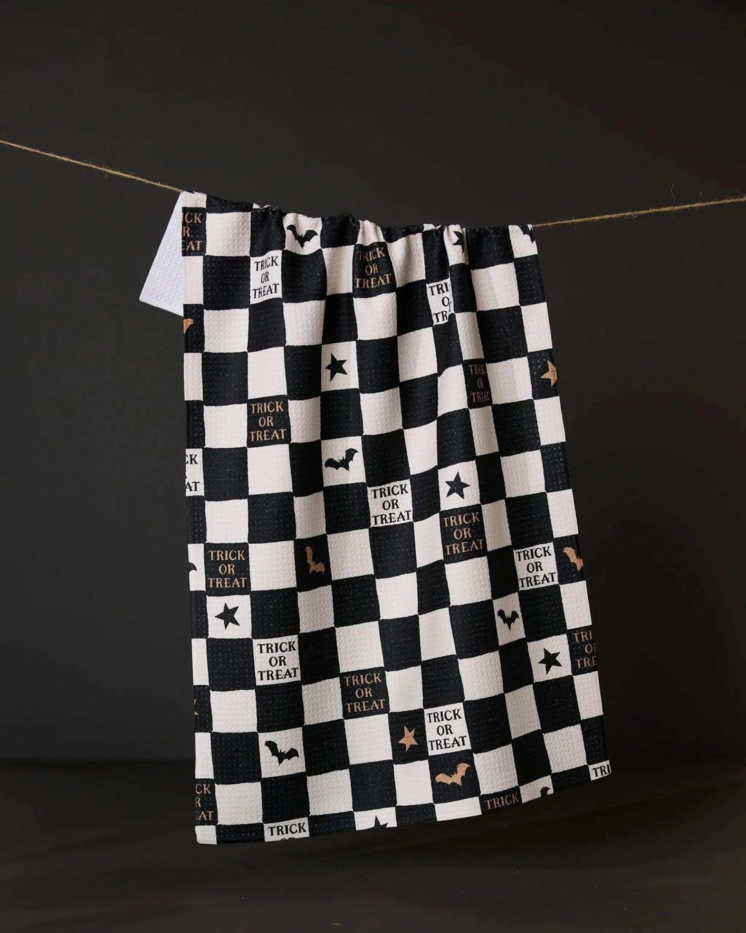 Black and white checkered blanket with Halloween text and graphics on a dark background