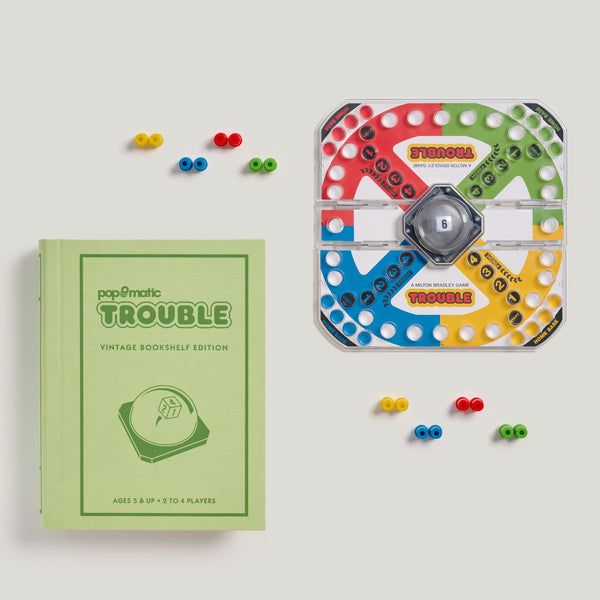 Board game 'Trouble' with green bookshelf edition packaging on a light gray background