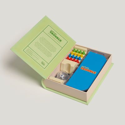 Toy set with a blue box and colorful pieces inside an open green box on a light gray background
