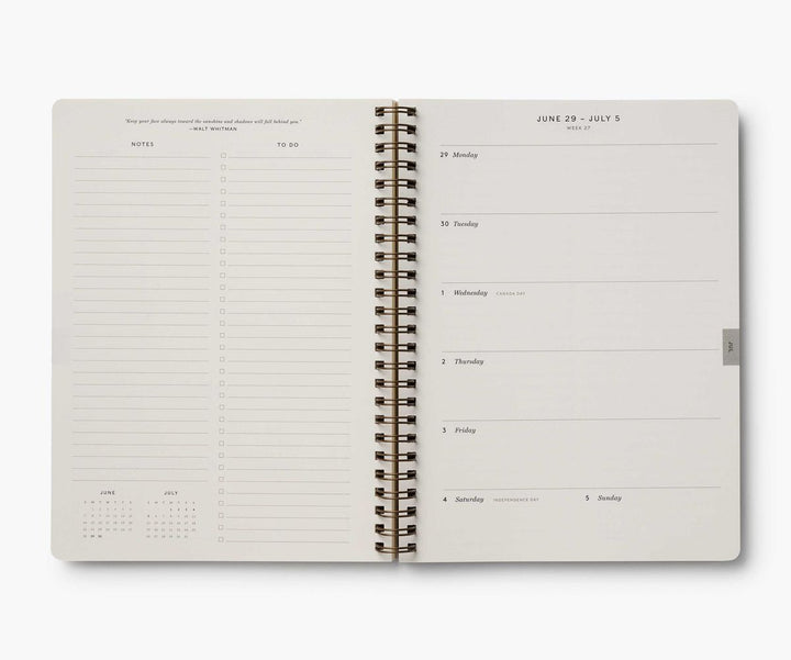Open spiral-bound planner with daily schedule on a white background