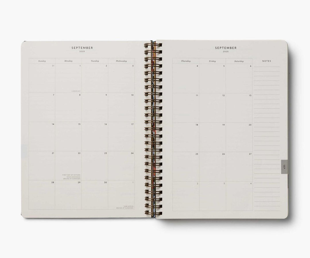Open spiral-bound planner showing a monthly layout on white background