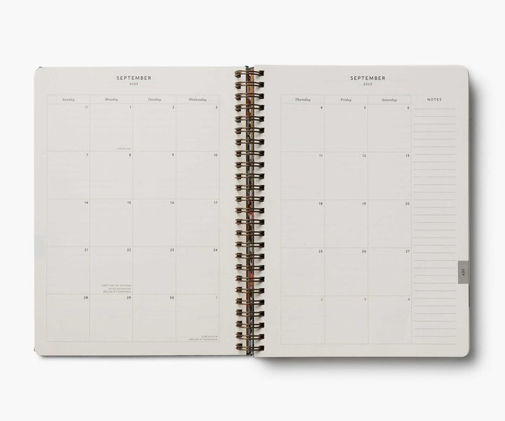 Open spiral-bound planner showing a monthly layout on white background
