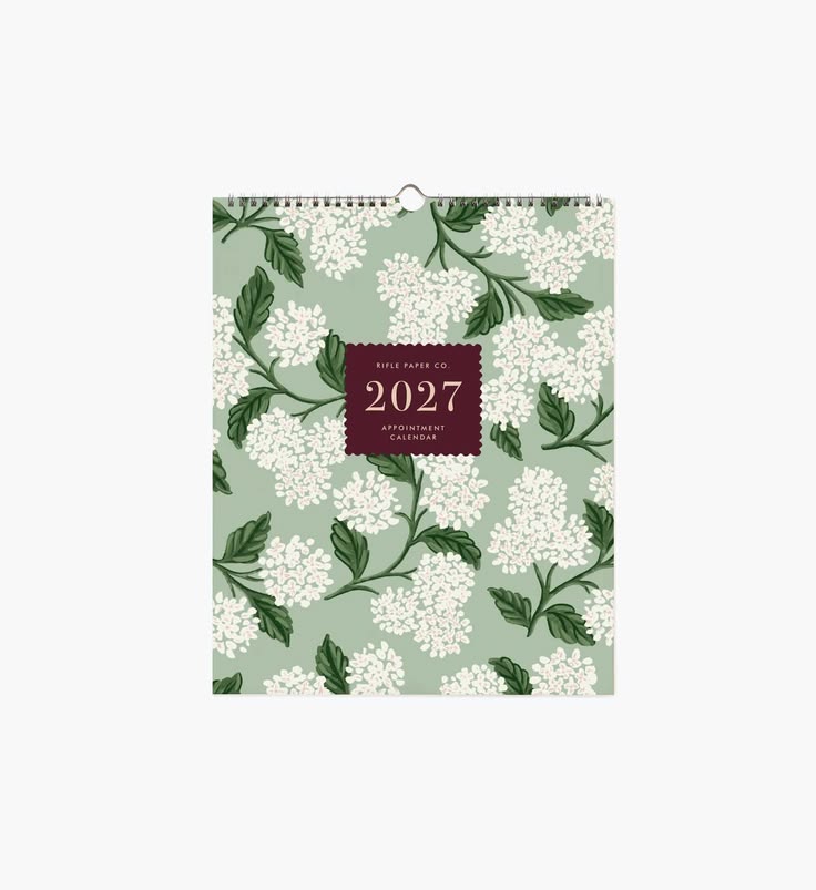 A 2027 wall calendar with a sage green background, white floral pattern, and a dark burgundy central label, shown against a plain white background.