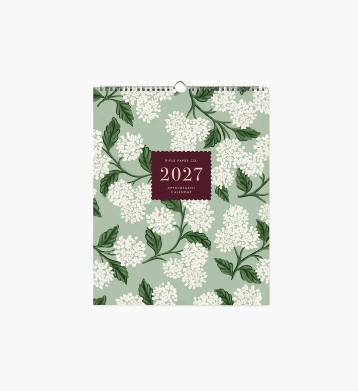 A 2027 wall calendar with a sage green background, white floral pattern, and a dark burgundy central label, shown against a plain white background.