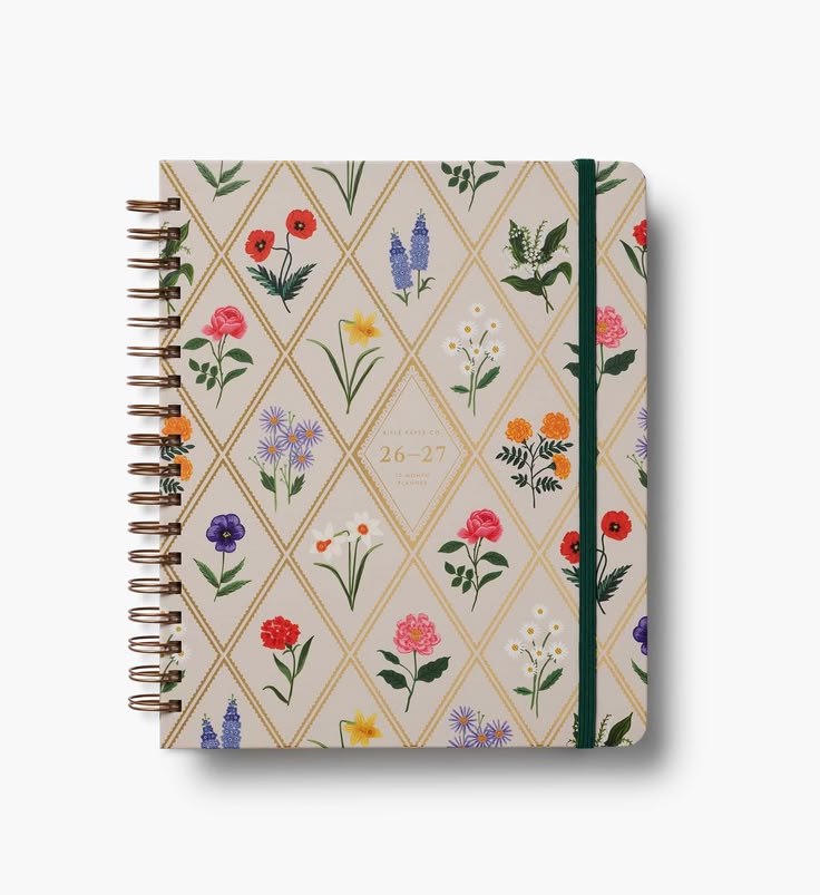 A spiral-bound planner or notebook with a cream cover decorated with a gold diamond lattice pattern and colorful wildflowers. It features a dark green elastic closure band and is photographed on a clean white background with a soft drop shadow.