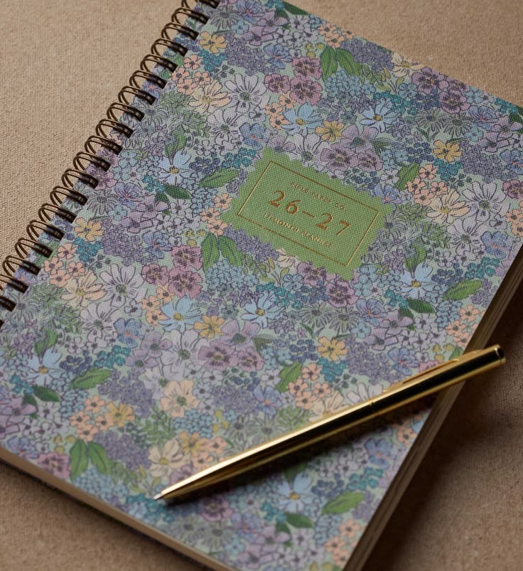 Floral-patterned notebook with a pen on a beige surface