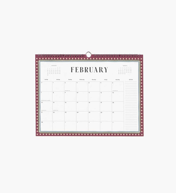 A hanging February calendar page with a burgundy border, white center, and printed monthly grid layout, shown against a light gray background.