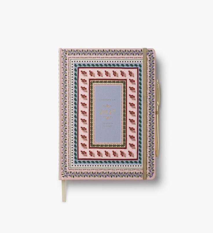 A decorative hardcover notebook with an intricate multicolor geometric border pattern and a central lavender panel featuring gold foil script, shown on a light gray background.