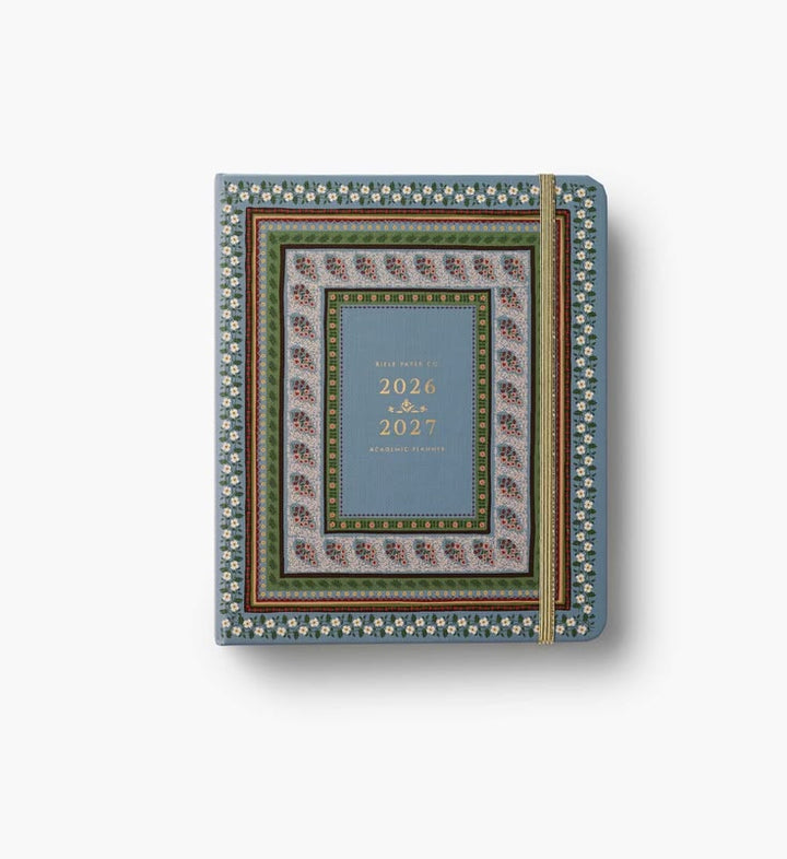 A decorative hardcover planner or notebook with a blue center panel, ornate multicolor border patterns, and gold text reading '2026 & 2027' on a white background.