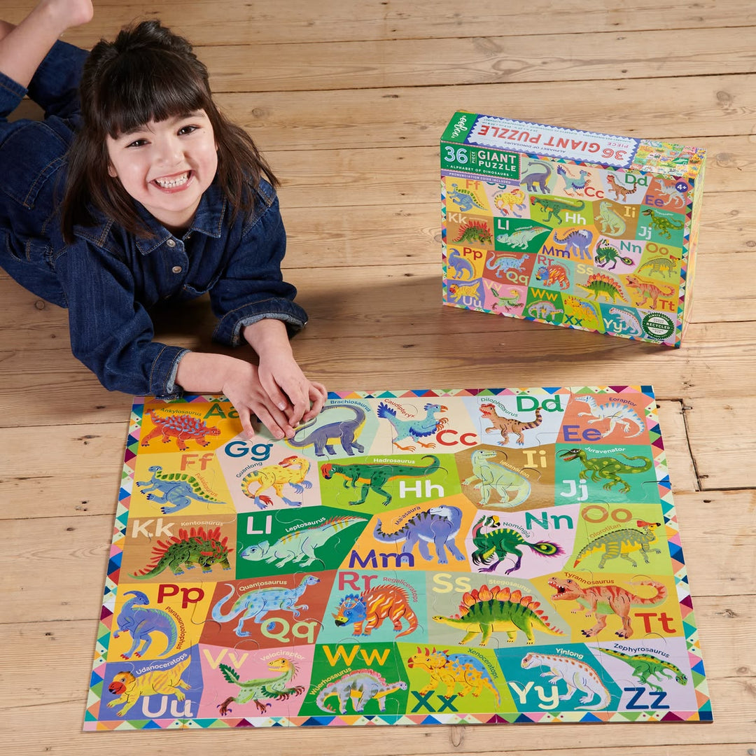 Child playing with a colorful alphabet and dinosaur puzzle on a wooden floor.