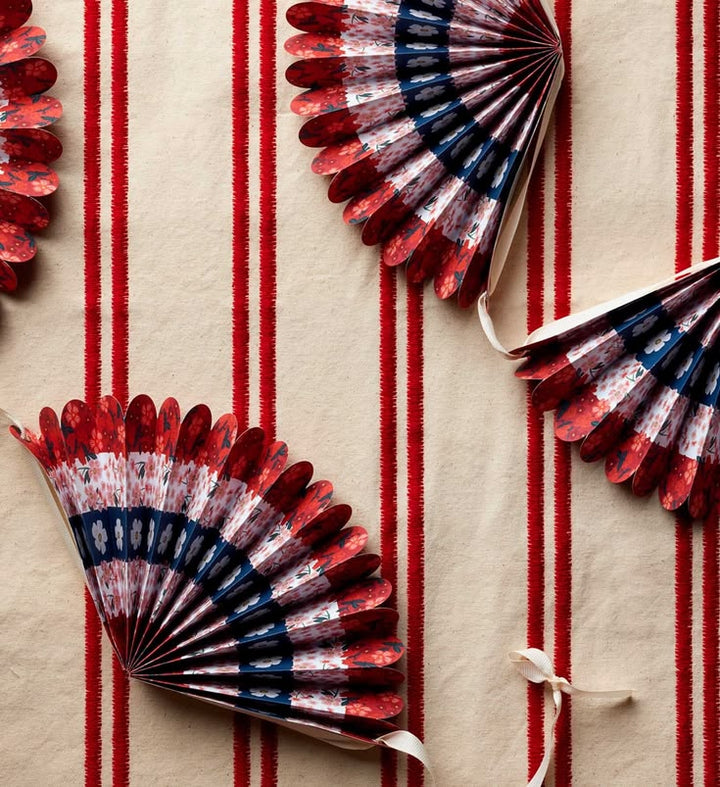 Decorative paper fans with red, white, and blue pattern on a red and beige striped background