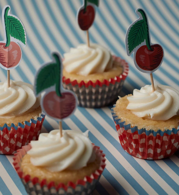 Cupcakes with white frosting and red and white checkered wrappers on a striped background