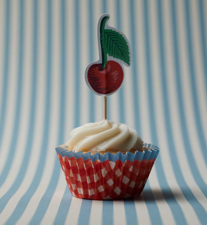 Cupcake with white frosting and a red cherry on top against a striped background