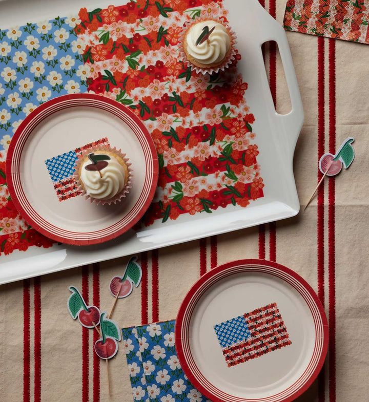 Cupcakes on decorative plates with American flag design on a floral tablecloth.