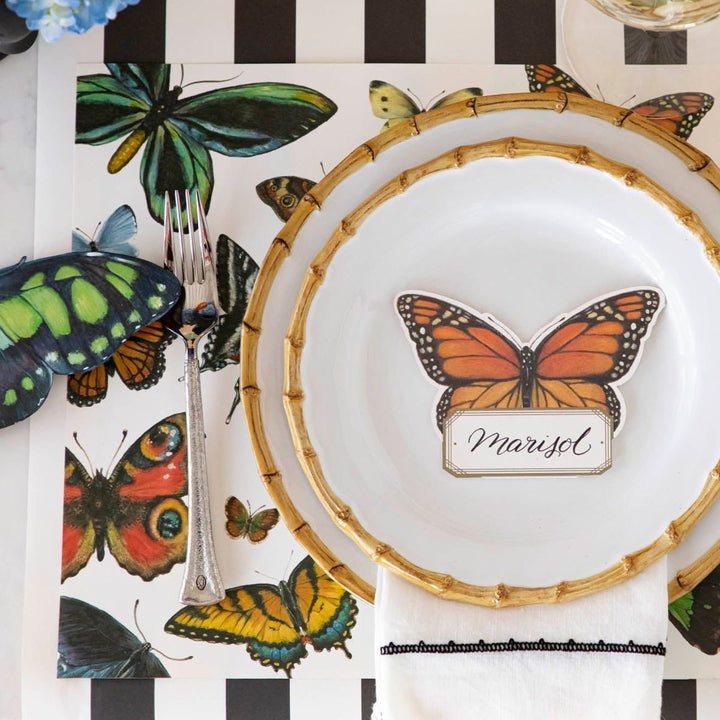 Butterfly-themed place setting with name card on a striped tablecloth