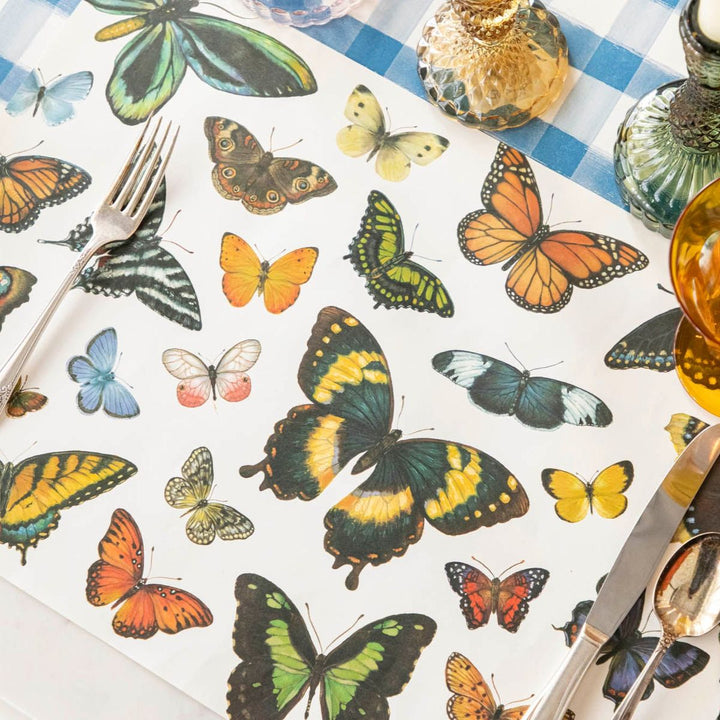 Butterfly-patterned placemat with cutlery on a checkered tablecloth.