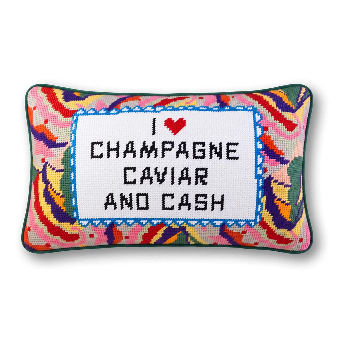 A rectangular decorative throw pillow with a colorful abstract patterned border and a central white stitched panel that reads “I ♥ CHAMPAGNE CAVIAR AND CASH” in black lettering, shown on a plain white background.