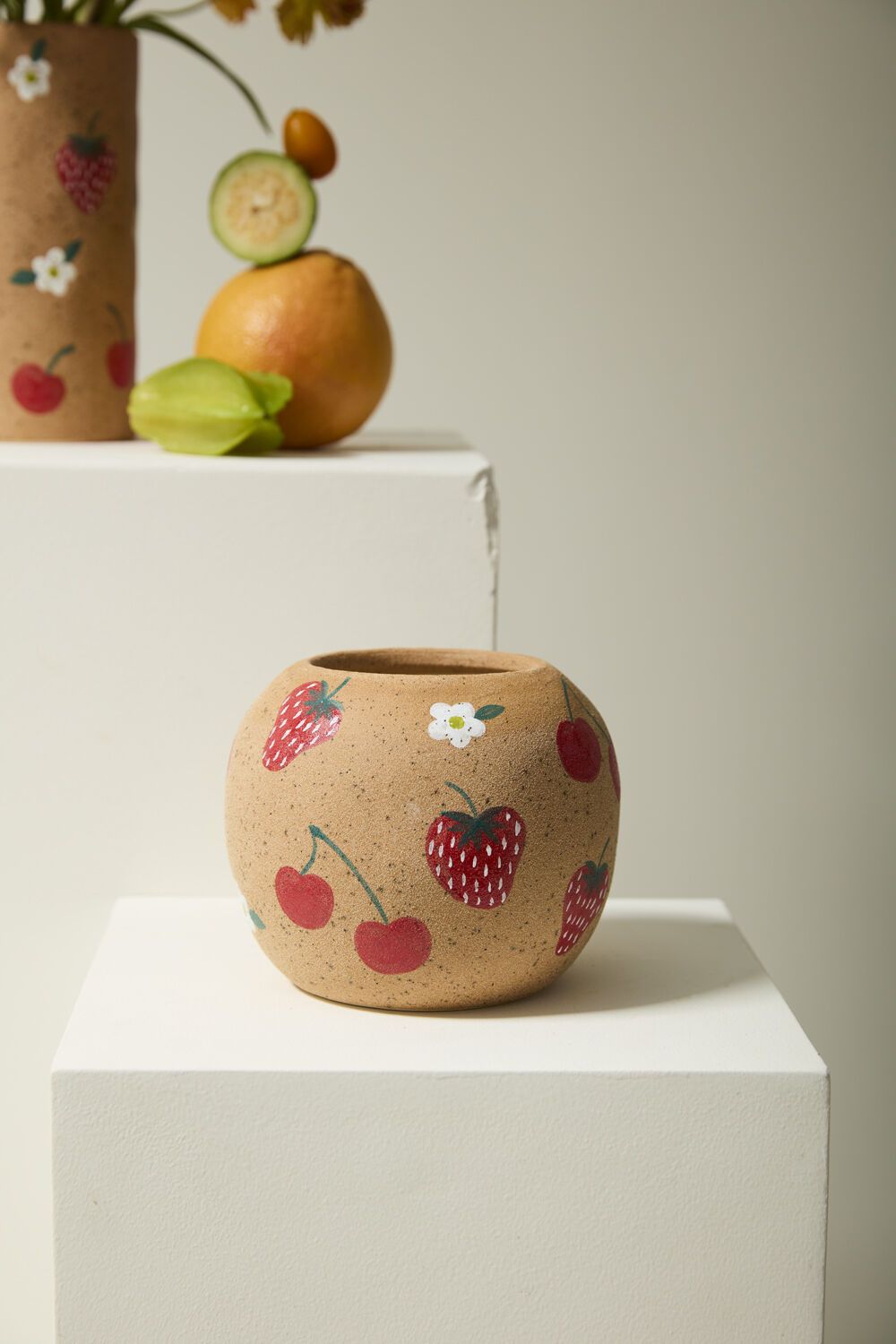 Ceramic pot with fruit patterns on a white surface