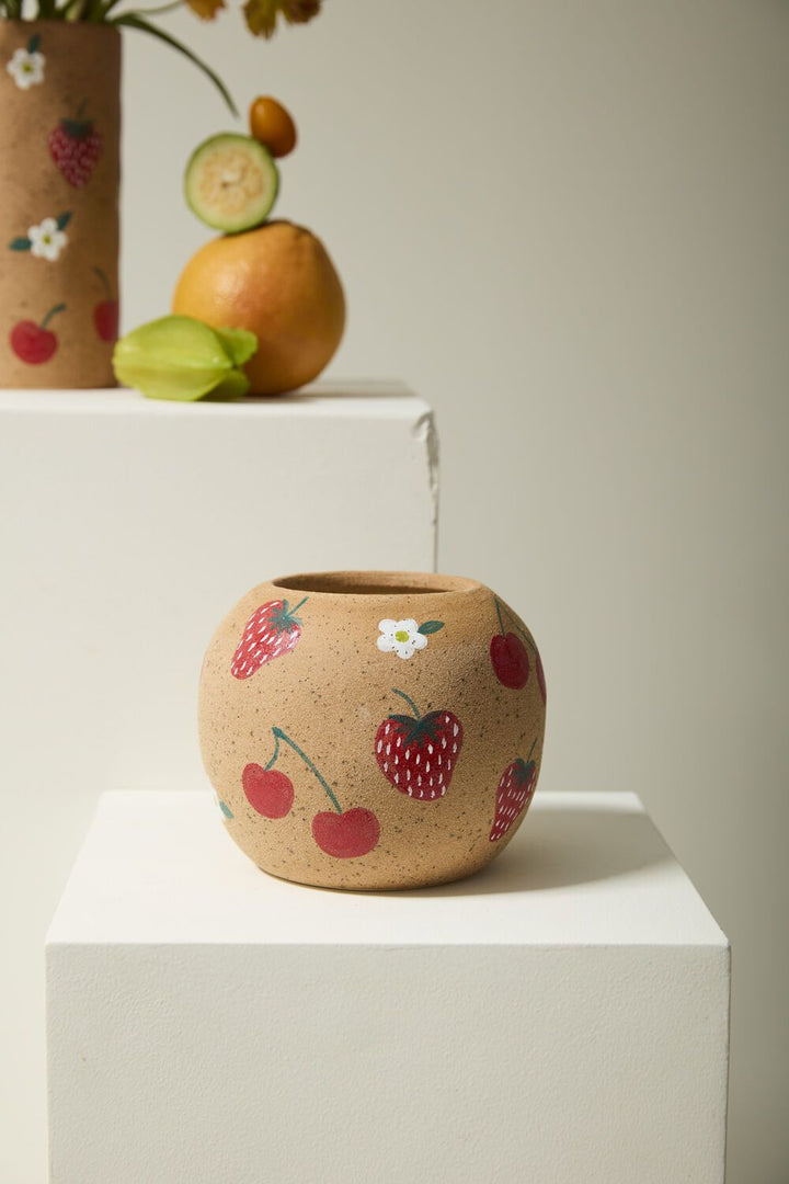 Ceramic pot with fruit patterns on a white surface