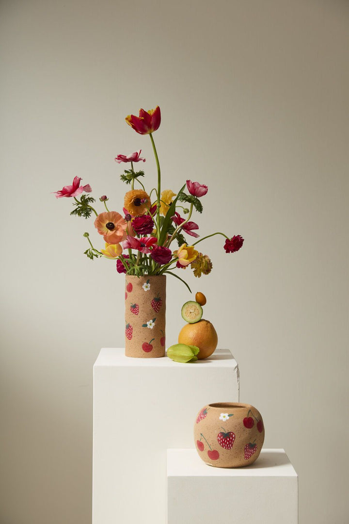 Floral arrangement in a decorative vase on a white pedestal with a plain background
