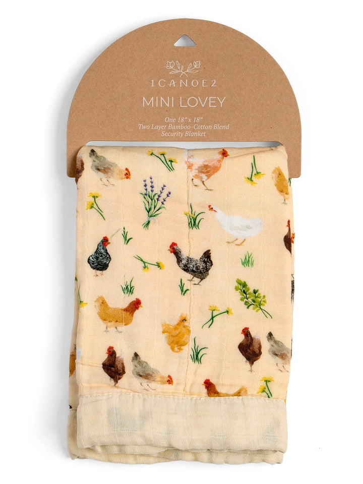 A packaged cotton muslin baby blanket by Icanez, featuring a colorful chicken and floral print on a light beige background, attached to a brown cardboard hanger.